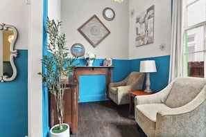 Una habitación con una decoración azul y blanca, que incluye dos sillones, una mesita con una lámpara y adornos en la pared.