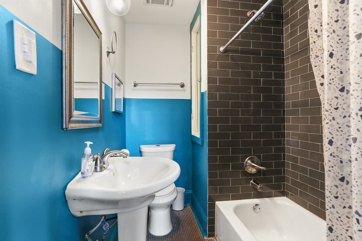 A bathroom with a white sink, a mirror, a toilet, and a bathtub.