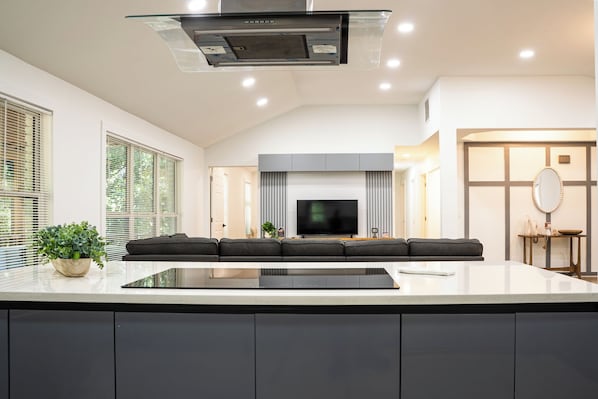 A modern kitchen with a central island, built-in appliances, and a flat-screen TV. - The White Brick Cottage located in Buckhead Area: Peaceful and Charming (Atlanta)