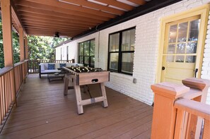 A covered outdoor area with a foosball table, a sofa, and a door. - The White Brick Cottage located in Buckhead Area: Peaceful and Charming (Atlanta)