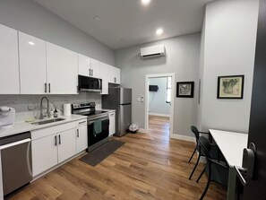 A modern kitchen with white cabinets, a stainless steel refrigerator, a microwave, and a dishwasher. - Brand New Modern 1BR in Old City Philadelphia (Philadelphia)