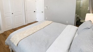 Ein Schlafzimmer mit Bett, Deckenventilator, Klimaanlage und einer Dusche.