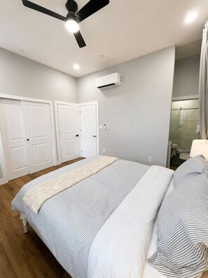 A bedroom with a bed, a ceiling fan, an air conditioning unit, and a shower area. - Brand New Modern 1BR in Old City Philadelphia (Philadelphia)