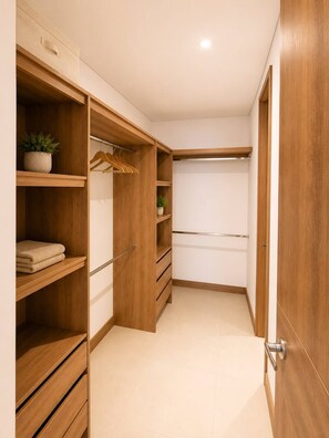 A walk-in closet with wooden shelving, a hanging rack, and a door. - ELIM Luxury Stay - Apartment El Poblado - Medellin (Medellín)
