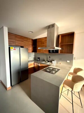A modern kitchen with a central island, stainless steel appliances, and wooden cabinetry. - ELIM Luxury Stay - Apartment El Poblado - Medellin (Medellín)