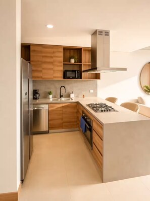 A modern kitchen with wooden cabinets, stainless steel appliances, a gas stove, and a microwave. - ELIM Luxury Stay - Apartment El Poblado - Medellin (Medellín)