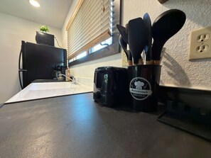 Un comptoir de cuisine avec une machine à café, une tasse et des ustensiles.