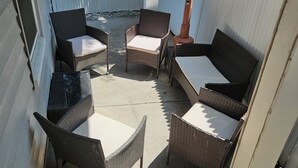Un área de estar al aire libre con mobiliario de mimbre y una mesa.