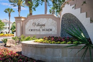 A sign for 'Villages of Crystal Beach' with a stone wall and landscaped garden. - Tahitian Treasure - Villages of Crystal Beach (Destin)