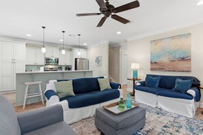 A modern living room with a sofa, ottoman, and a ceiling fan. - Tahitian Treasure - Villages of Crystal Beach (Destin)