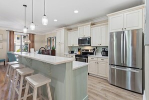 A modern kitchen with a central island, stainless steel appliances, and light-colored cabinetry. - Tahitian Treasure - Villages of Crystal Beach (Destin)