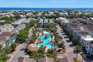 A resort with a central swimming pool, multiple buildings, and a view of the ocean. - Tahitian Treasure - Villages of Crystal Beach (Destin)
