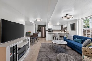 A modern living room with a TV, sofa, and dining area. - Two Midtown Reno Apartments | Sleeps 8 (Reno)