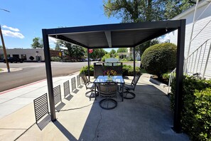 Een terras met overdekte tafel en stoelen, een stopbord en een gebouw op de achtergrond.