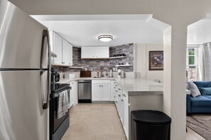 A modern kitchen with white cabinets, a black refrigerator, and a built-in oven. - Two Midtown Reno Apartments | Sleeps 8 (Reno)