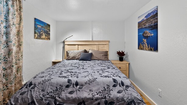 A bedroom with a bed, nightstand, and two wall-mounted pictures. - Lander & Mt Rose Duo | Near Midtown & Downtown (Reno)