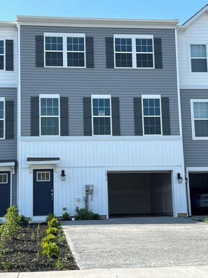 A multi-story residential building with a garage, a front door, and a small garden area. - Beautiful Townhouse 4 bedroom 3  bathroom in Fogelsville PA (Fogelsville)