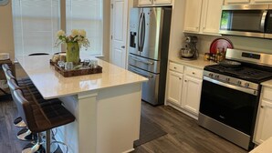 A modern kitchen with white cabinetry, stainless steel appliances, and a central island with seating. - Beautiful Townhouse 4 bedroom 3  bathroom in Fogelsville PA (Fogelsville)