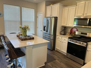 A modern kitchen with white cabinetry, stainless steel appliances, and a central island with seating. - Beautiful Townhouse 4 bedroom 3  bathroom in Fogelsville PA (Fogelsville)