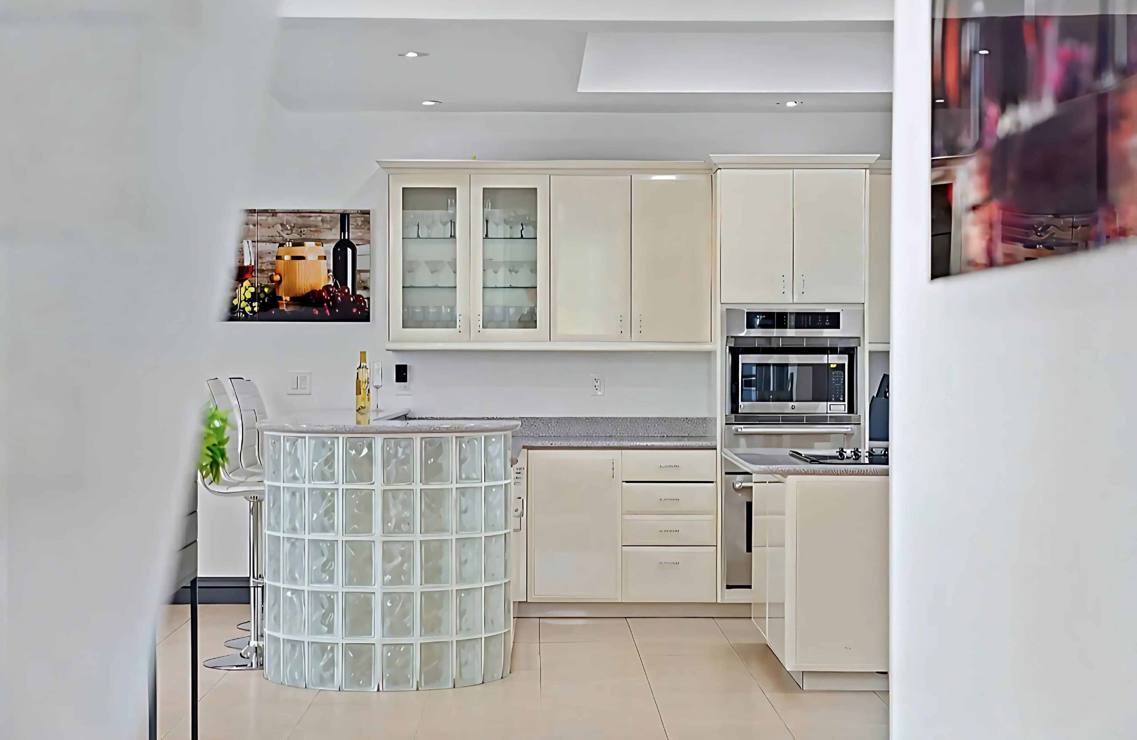A modern kitchen with white cabinets, a built-in oven, and a glass-topped island.