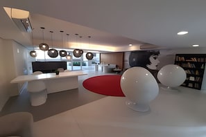 Ein modernes Interieur mit einer zentralen Kochinsel, Pendelleuchten und einer roten Akzentwand.