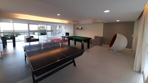 Ett modernt, inomhusutrymme för rekreation med ett biljardbord, ett bord för vanlig biljard och ett bord för bordtennis.