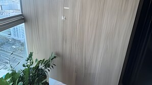 Ett rum med ett stort fönster, utsikt över stadsbilden och en krukväxt på fönsterbrädan.