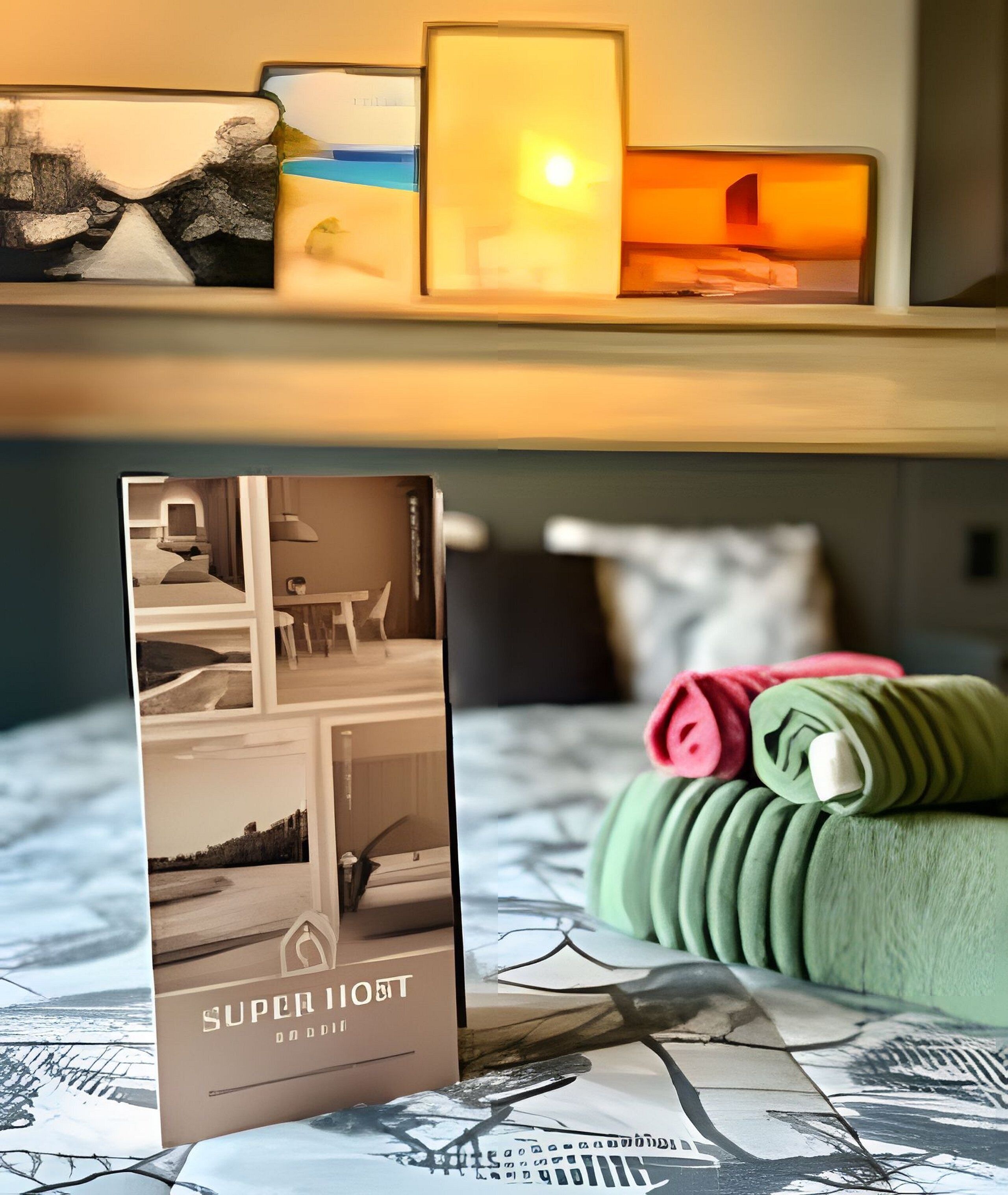 Habitación de hotel con cama, mesita de noche con lámpara, toalla verde doblada y un folleto sobre la cama.