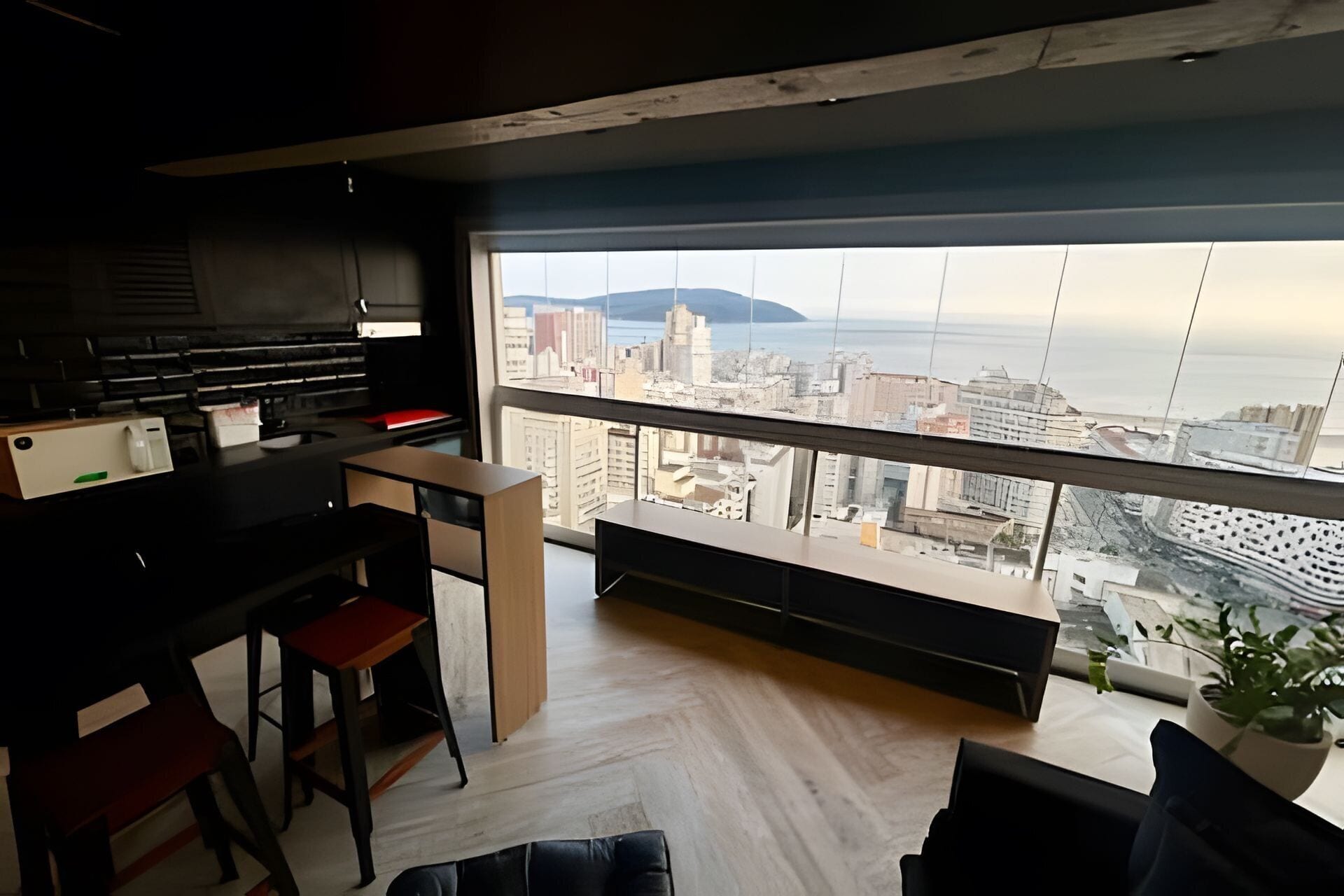 A modern living space with a city view, a kitchen area, and a seating area.