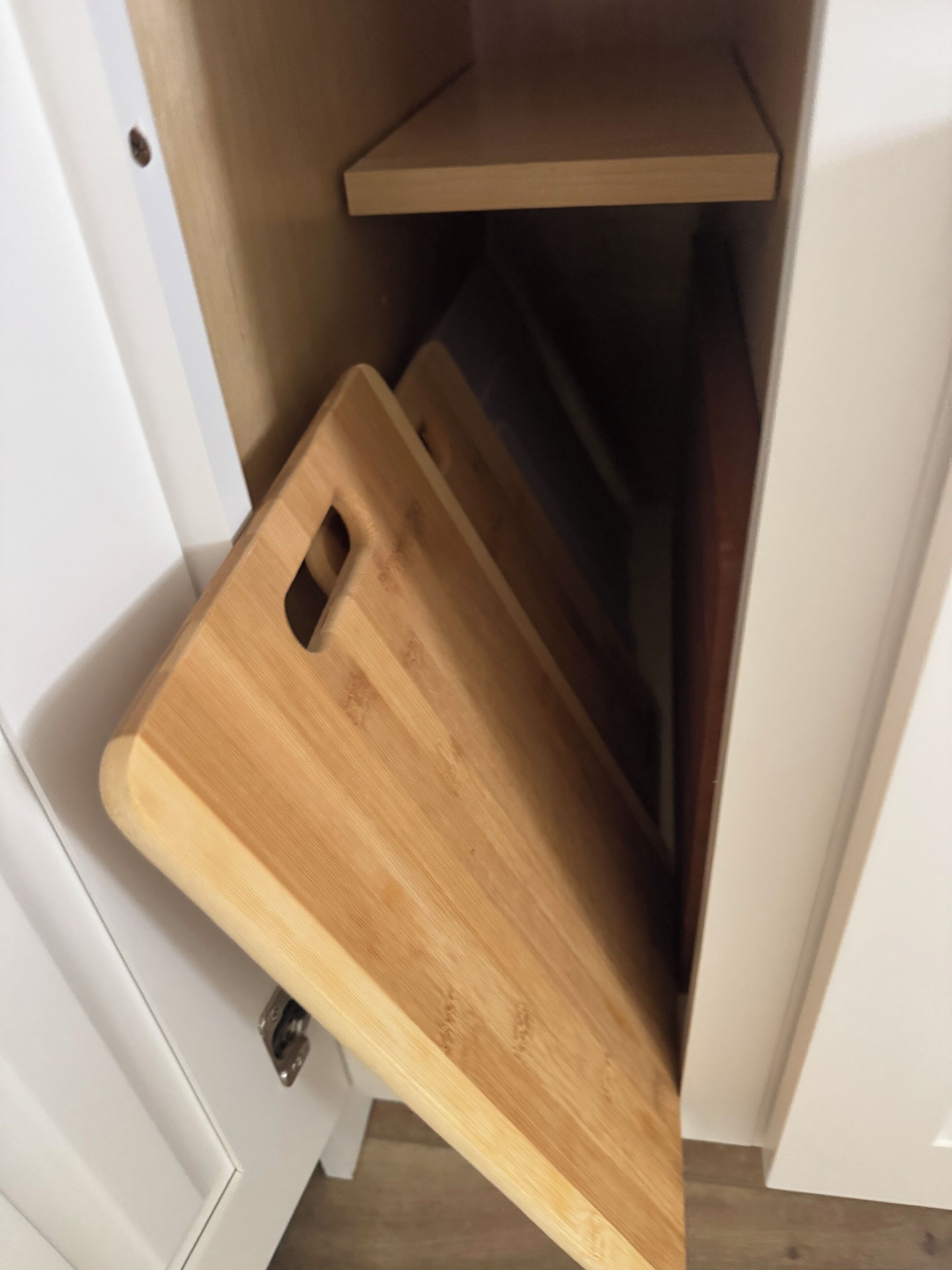 Puinen leikkuulauta nojaa valkoista ovea vasten, ja sen yläpuolella on hylly.