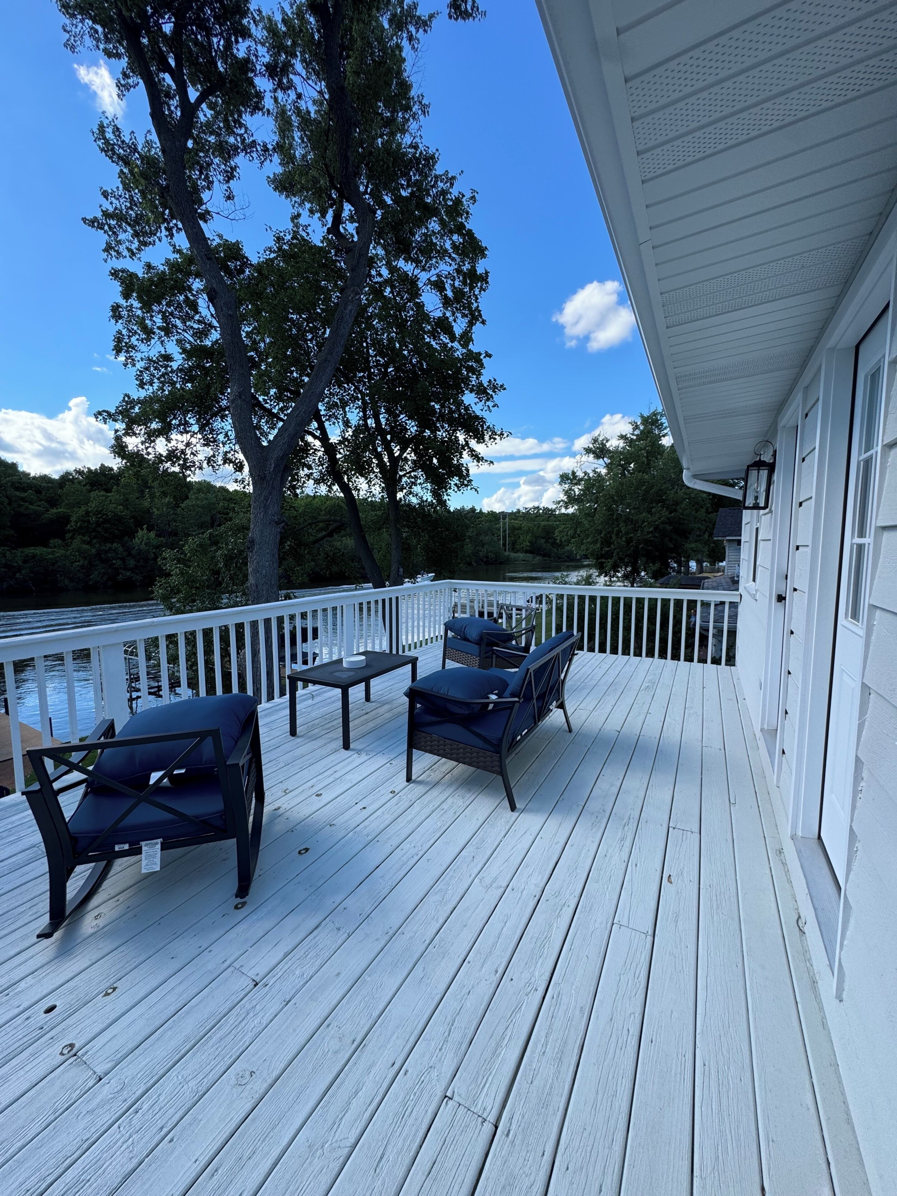 A wooden deck with outdoor furniture, a railing, and a view of a body of water.