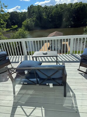 A deck with a table and chairs, overlooking a river and forest.