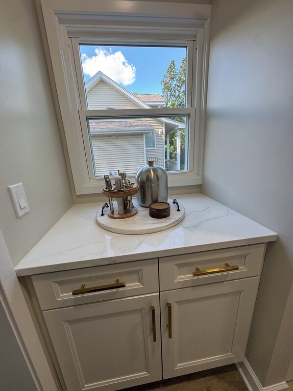 A kitchen with a window, white cabinets, and a marble countertop.
