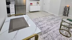 Una cocina moderna con gabinetes blancos, un refrigerador de acero inoxidable, un microondas y un televisor de pantalla plana montado sobre la encimera.