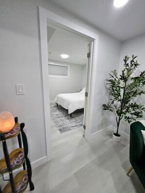 Ein Zimmer mit einem Bett, einer Topfpflanze und einem Sessel mit einer Lampe.