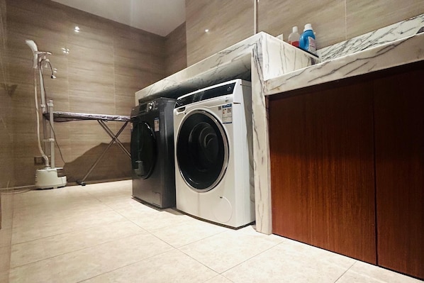Un espace buanderie compact comprenant un lave-linge, un étendoir et une porte en bois.
