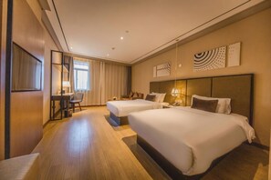 Une chambre d’hôtel avec deux lits, un bureau, une chaise et un téléviseur.