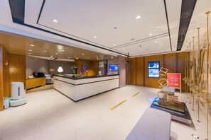 A modern hotel reception area with a reception desk, a coffee machine, a digital screen, and a decorative installation. - Yitel Premium (Shanghai)