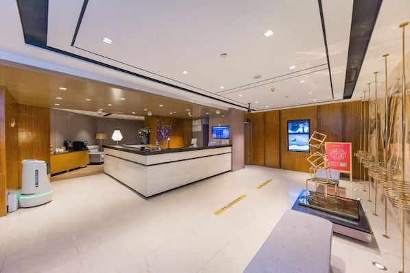 A modern hotel reception area with a reception desk, a coffee machine, a digital screen, and a decorative installation. - Yitel Premium (Shanghai)