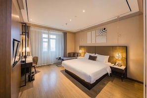 Une chambre d’hôtel moderne avec un grand lit, des tables de chevet, un bureau et une chaise.