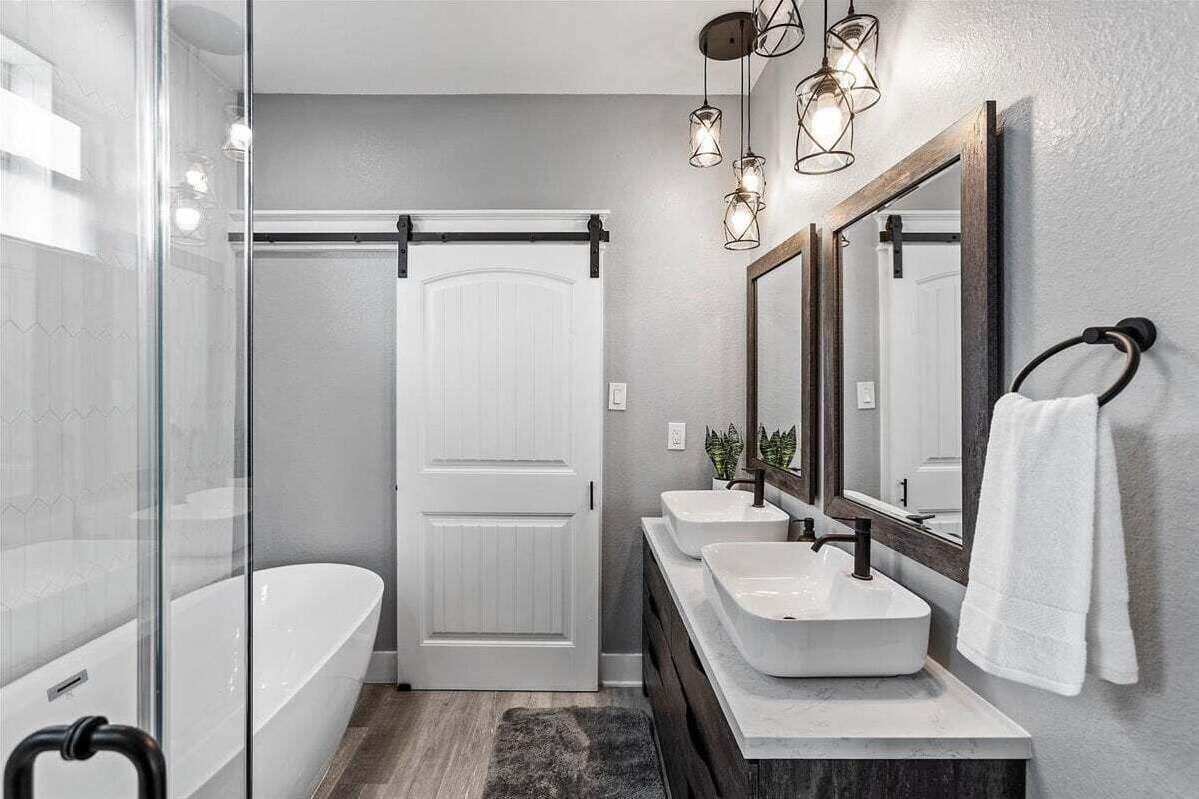 Un baño moderno con cabina de ducha de vidrio, una bañera blanca y un tocador con dos lavamanos.