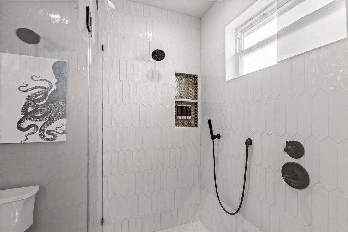 Ducha con diseño de azulejos hexagonales, cabina de vidrio y ducha empotrada.