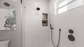 Ducha con diseño de azulejos hexagonales, cabina de vidrio y ducha empotrada.