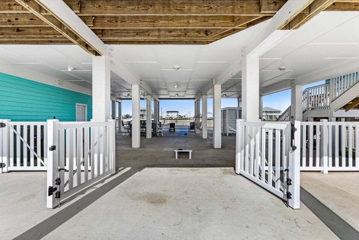 Un espacio interior con piso de concreto, barandas blancas y vista al exterior.