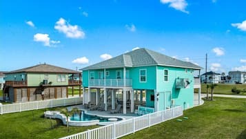 A two-story house with a swimming pool, a fenced yard, and a clear blue sky.