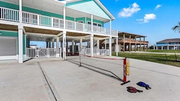 A two-story building with a covered porch, a tennis court, and a pool area.