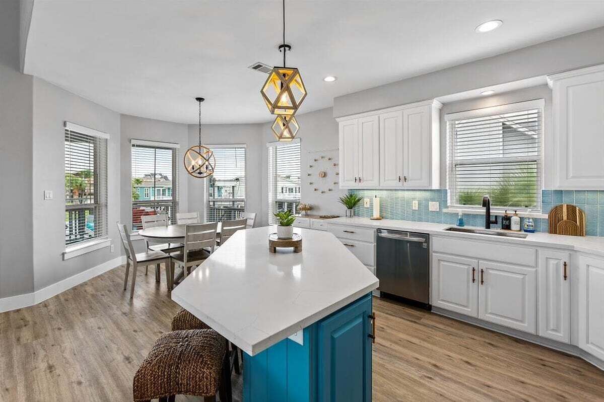 A modern kitchen with white cabinets, a central island, and pendant lighting.