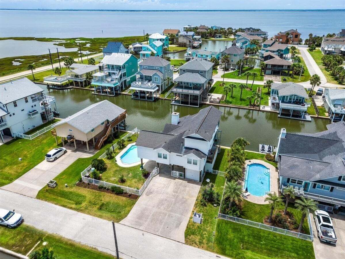 A residential area with houses, a swimming pool, and a body of water.
