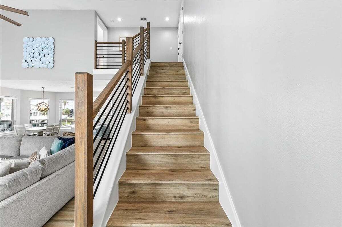 Una escalera de madera con escalones y barandilla, que lleva a un piso superior.