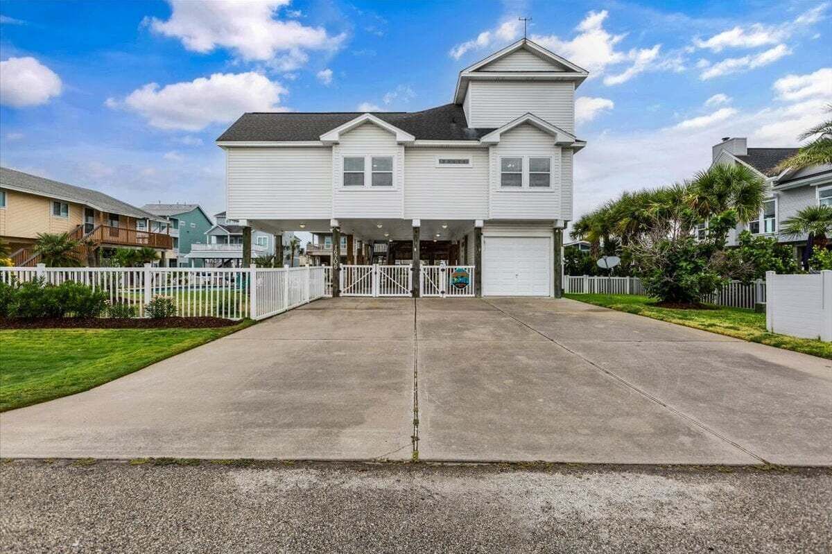 A two-story residential building with a covered porch, a garage, and a driveway.